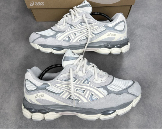 Pair of gray and white running shoes with a brown Asics box on a gray surface