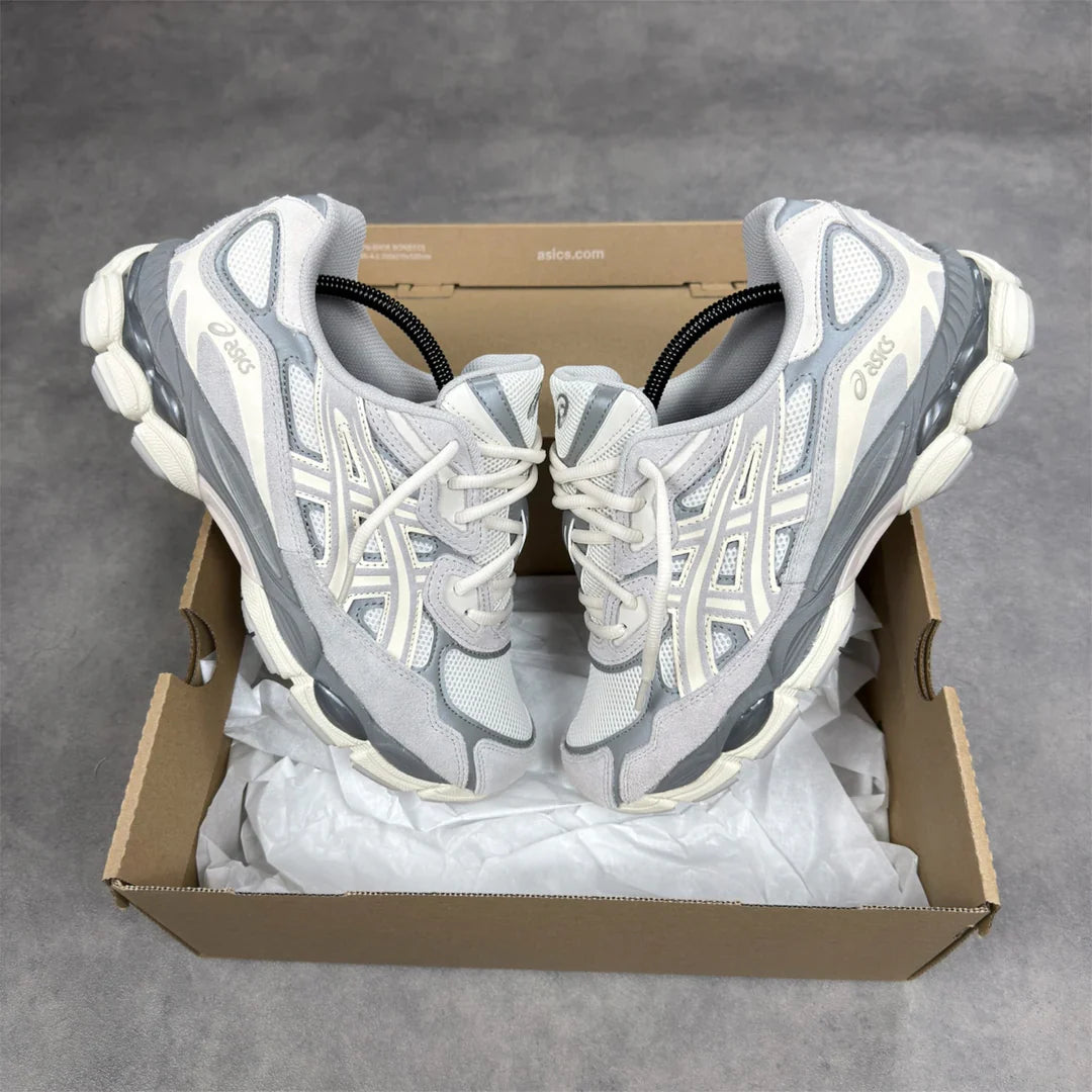 Pair of gray and white running shoes in a cardboard box on a gray background