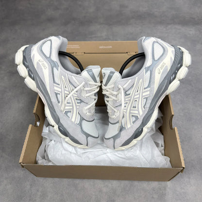Pair of gray and white running shoes in a cardboard box on a gray background